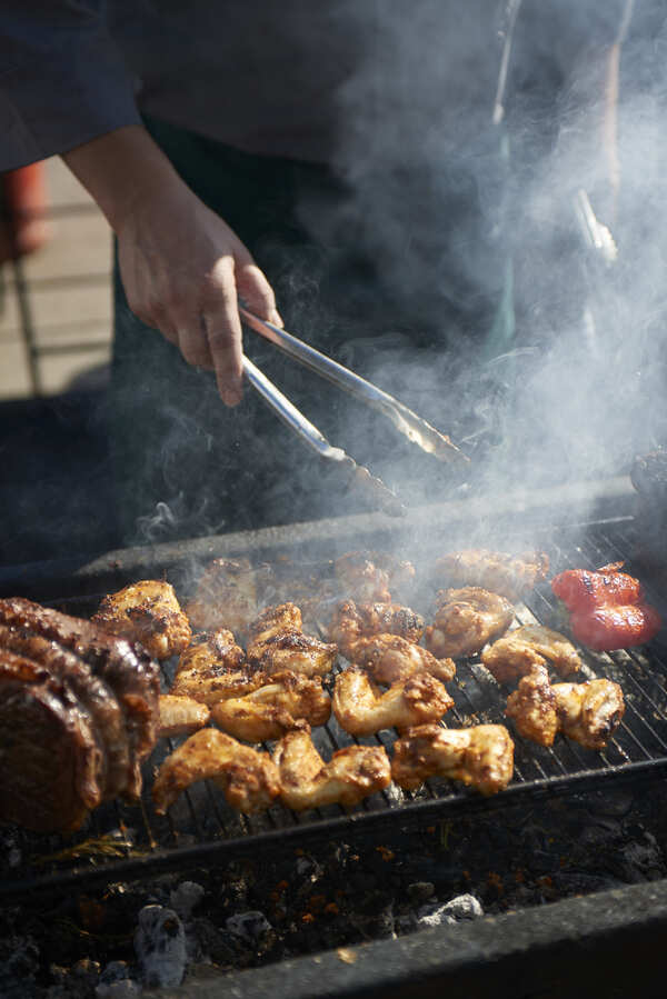 Chicken and lamb cooking over charcoal with smoke rising